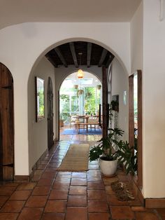 an archway leading to a dining room and kitchen area with potted plants on the floor