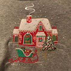 a house with a christmas tree and sleigh on it's front is embroidered onto the back of a t - shirt