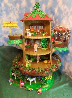 a doll house with lots of trees and animals on the top floor, in front of a blue wall