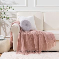 a living room with a white couch and pink throw blanket on top of the sofa