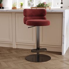 a red chair sitting on top of a wooden floor next to a kitchen countertop