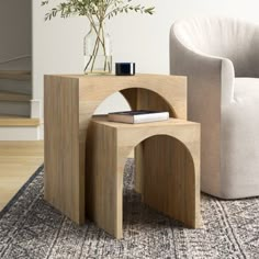 a wooden table sitting on top of a rug next to a white chair and plant