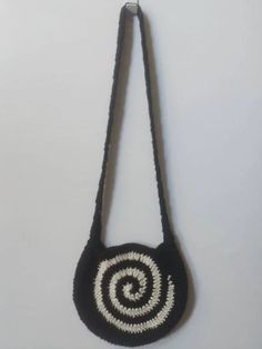 a black and white bag hanging from a hook on a wall with a spiral design