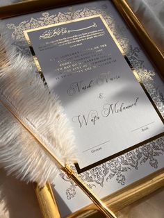 the wedding stationery is in gold, silver and white with a feather on it