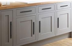 a kitchen with gray cabinets and wood counter tops