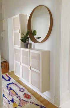 a room with a rug, mirror and white cabinet in the corner on the wall