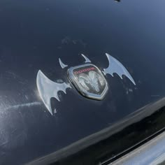 an emblem on the hood of a black car with bats painted on it's side