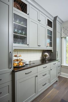 a kitchen with white cabinets and black counter tops, along with wooden floors is shown in front of a large window