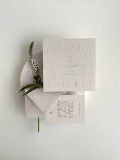 the wedding stationery is laid out on top of each other, with a single flower sticking out of it