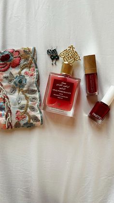 the contents of a purse are laid out on a white sheet with red and gold accents