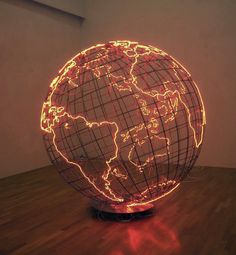 an illuminated globe sitting on top of a wooden floor