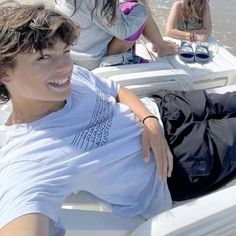 two young people sitting on a boat in the water, one is smiling at the camera