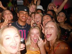 a group of young people standing next to each other with their hands in the air