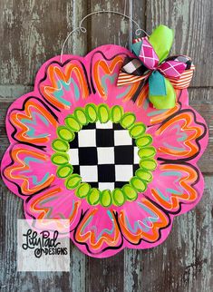 a pink and green flower shaped door hanger with a checkered design on it