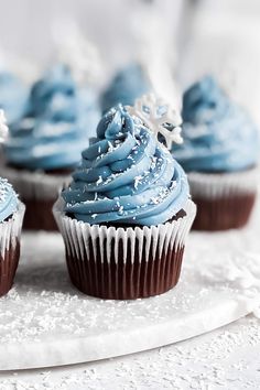 cupcakes with blue frosting and sprinkles on a white plate