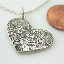 two fingerprints in the shape of a heart on a necklace next to a penny