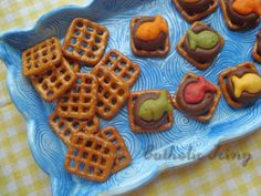 a blue plate topped with cookies and pretzels on top of a checkered table cloth