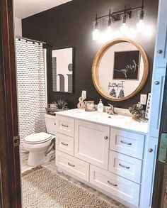 the bathroom is decorated in black and white with an oval mirror on the wall above the sink