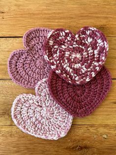 three crocheted hearts sitting on top of a wooden table