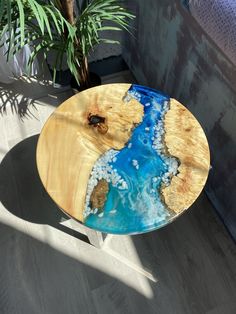 a wooden table with blue and white paint on it in a room next to a potted plant