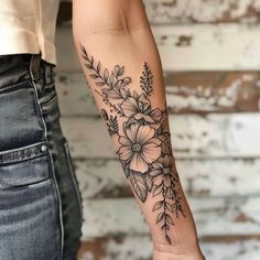 a woman's arm with flowers and leaves tattooed on the left side of her arm