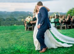 a bride and groom walking down the aisle at their outdoor wedding ceremony with guests in the background