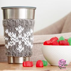 a knitted cup cozy next to a bowl of gummy bears