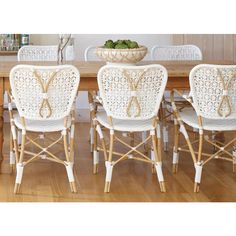 a dining room table with white wicker chairs