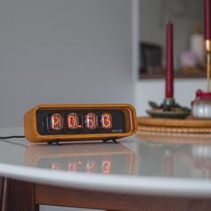 an alarm clock sitting on top of a table next to a candle and some candles