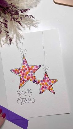 two stars are hanging from strings on a card