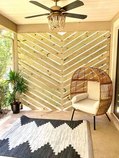 a room with a ceiling fan, chair and rug on the floor in front of it