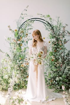 a woman standing in front of an arch with flowers