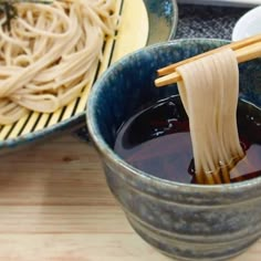 chopsticks sticking out of a bowl filled with liquid and noodles on the side