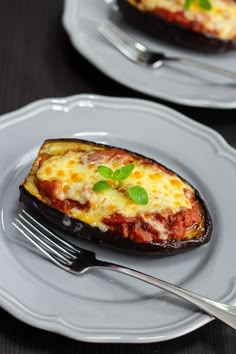 an eggplant stuffed with cheese is on a plate next to a fork and knife