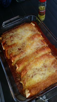 a casserole dish with cheese and sauce on the side