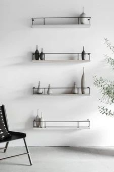 three shelves with vases and plants on them against a white wall in an empty room