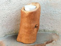 a wooden candle holder sitting on top of a cement floor