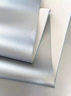 two sheets of white leather on top of each other, one is shiny and the other has