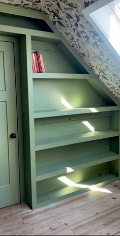 a green book shelf under a slanted roof