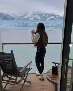 a woman standing on the deck of a boat looking out at an iceberg in the distance