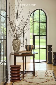 a table with vases and plants on top of it in front of a large window