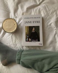 a person's feet on a bed next to a book about jane eyre