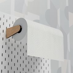 a roll of toilet paper is hanging on a wall with holes in it and a wooden handle