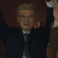 a man in a suit and tie raising his hands