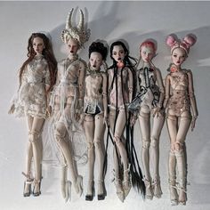 five dolls are lined up in the same row, all wearing different outfits and hair accessories