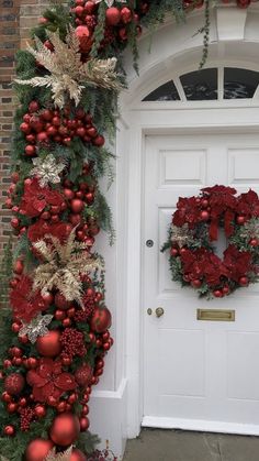 a christmas wreath on the front door of a house decorated with red balls and greenery