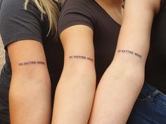 two women with matching tattoos on their arms, both holding each other's hands