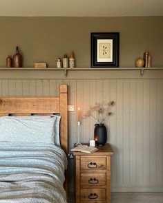 a bed sitting next to a wooden dresser with a lamp on it's side