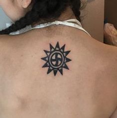 the back of a woman's neck with a sun tattoo on her left shoulder