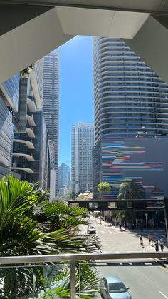 a city street with tall buildings and palm trees in the foreground, on a sunny day